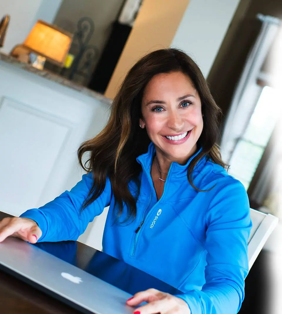 cheerful girl smiling at camera while using laptop